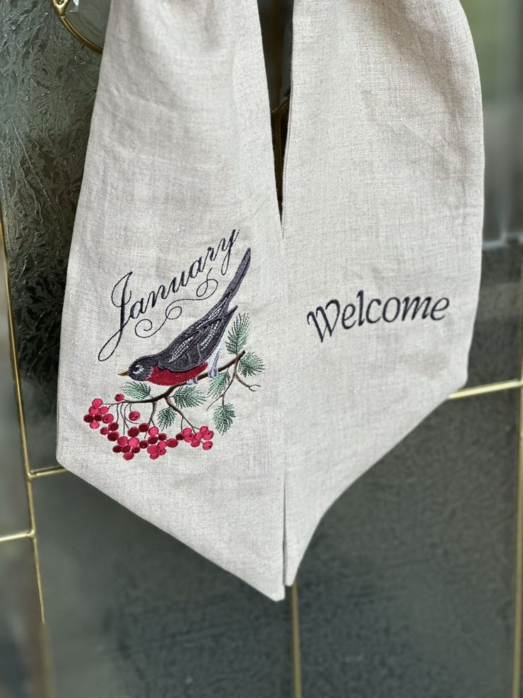 two tea towels hanging on a rack with the words january and welcome written on them