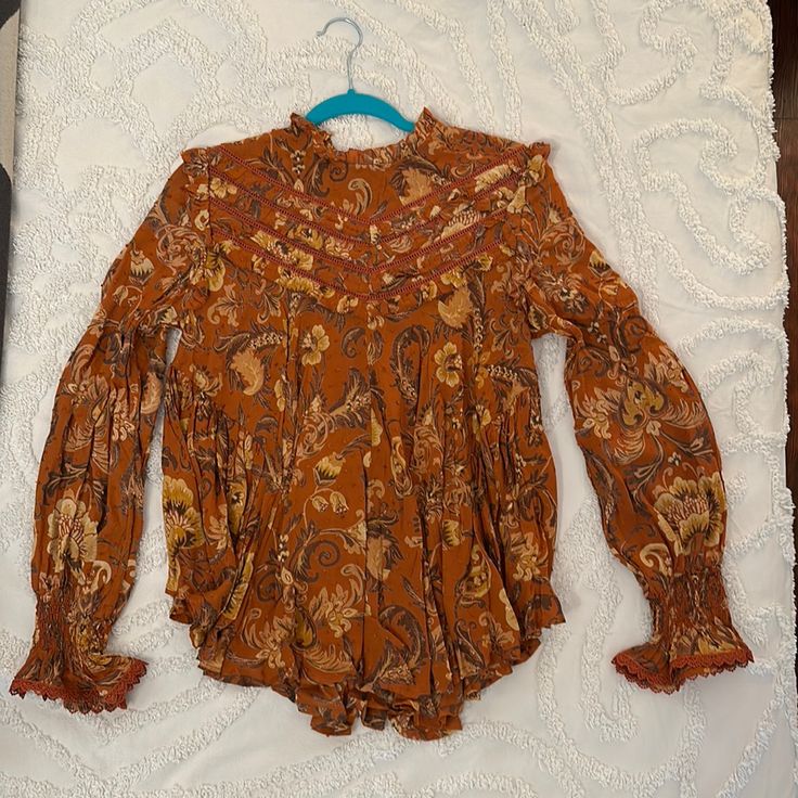 Nwt Aurora Blouse Size Medium. Sweet Ruffle Details On The Shoulders, Neck Line, Bust And Back. Ruched At The Wrists With Lace Trimmed Flare. Predominantly Rust Color With Tan And Brown Shades Throughout Flowy Orange Blouse With Floral Print, Orange Flowy Long Sleeve Tops, Flowy Orange Floral Print Blouse, Printed Long Sleeve Peasant Top For Fall, Vintage Orange Fall Tops, Orange Long Sleeve Printed Tops, Brown Flowy Long Sleeve Tops, Brown Boho Print Blouse For Fall, Orange Printed Long Sleeve Tops