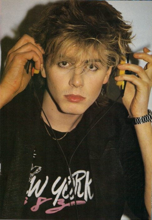 a young man is talking on his cell phone while wearing a black t - shirt