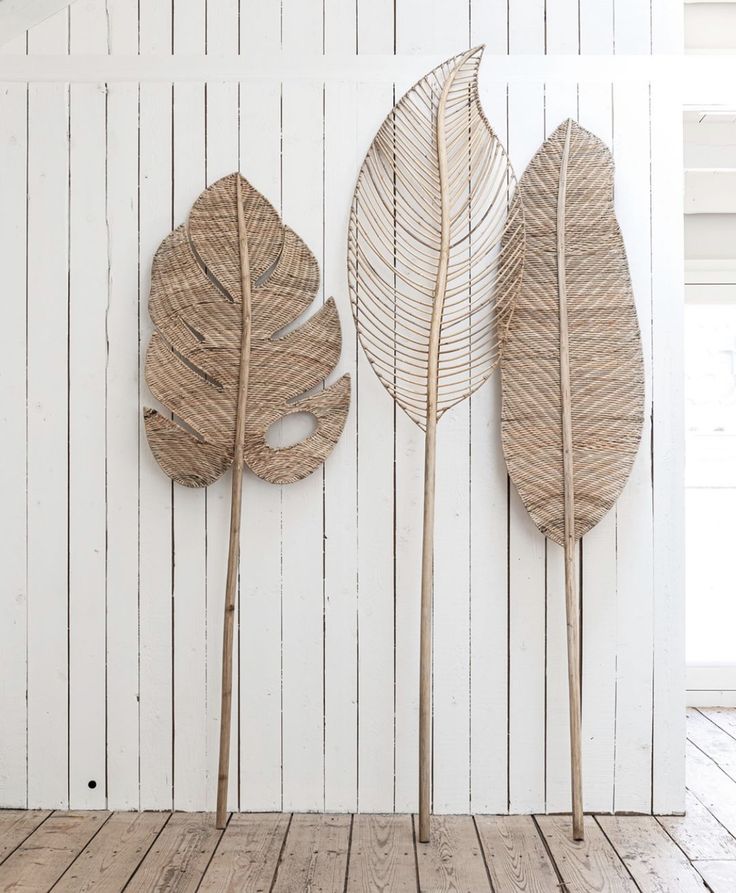 three large leaves are placed on the wall next to each other, one is made out of wicker