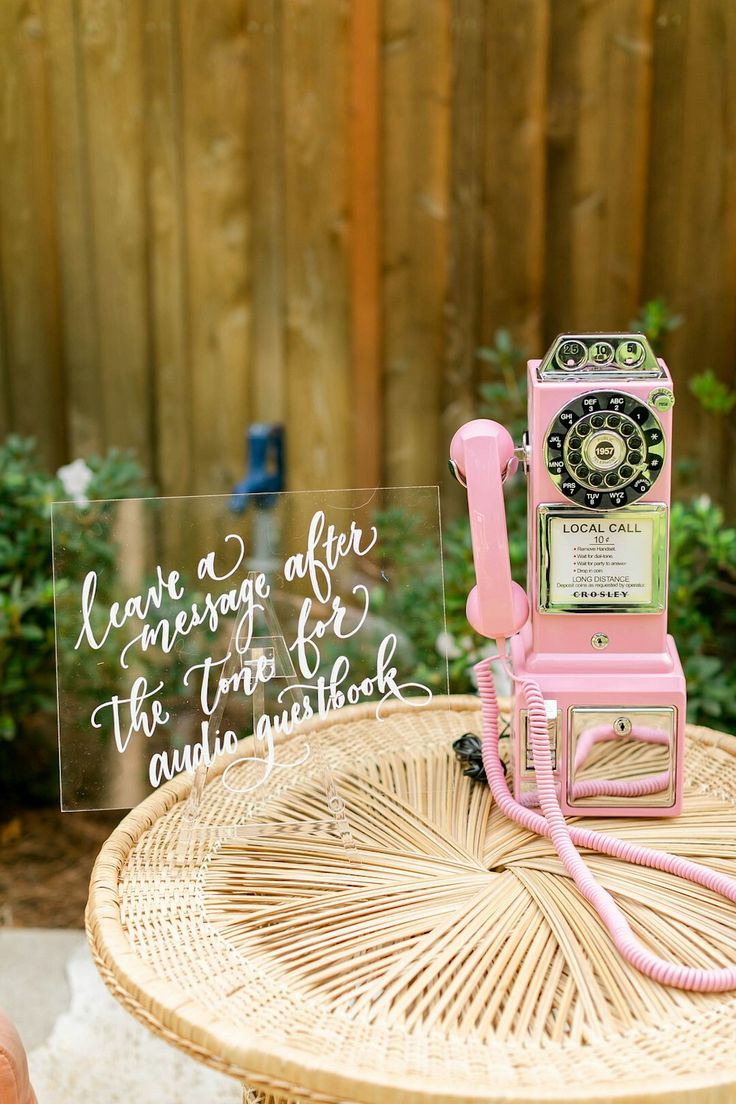 a pink phone sitting on top of a table next to a sign that says please after the telephone call and wait