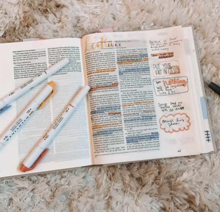 an open bible with markers and pens laying on the floor next to it's contents