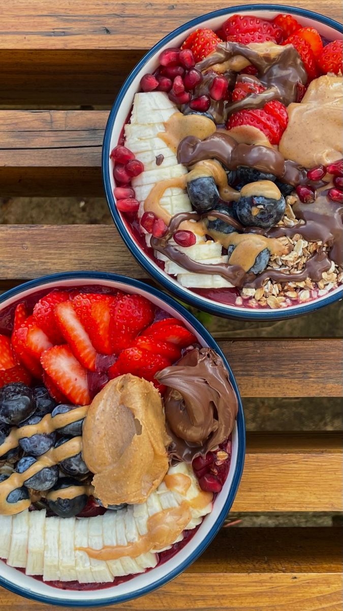 two bowls filled with different types of fruit on top of a wooden table next to each other