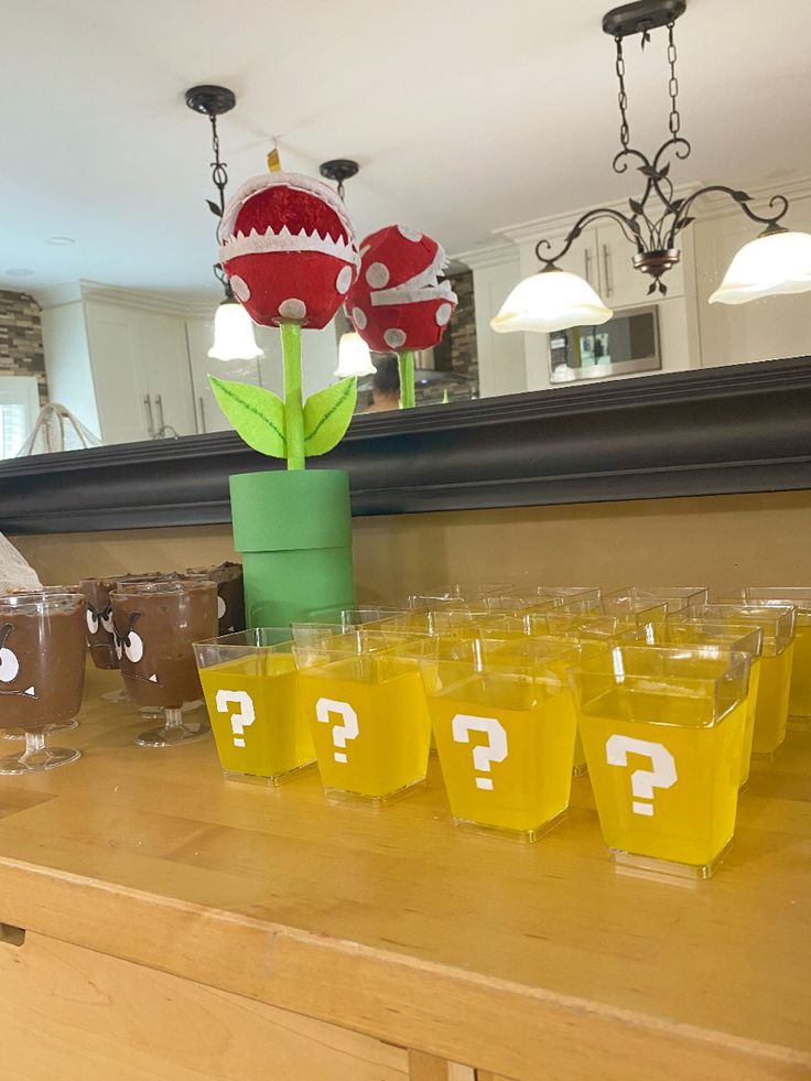 there are many cups on the counter with question marks in them and a flower sticking out of one