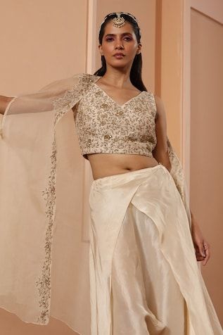 Ivory blouse featuring floral embroidery and tie-up detailing on the back. Paired with a draped dhoti and embroidered sheer cape. - Aza Fashions Elegant Fitted Embroidered Top With Traditional Drape, Elegant Sleeveless Embroidered Top For Weddings, Elegant Raw Silk Embroidered Top For Wedding, Elegant Embroidered Raw Silk Top For Wedding, Beige Silk Tops For Wedding, Silk Dupatta Top For Wedding, Silk Top With Dupatta For Wedding, Silk Wedding Top With Dupatta, Beige Silk Top For Wedding