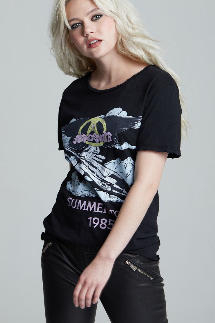 An iconic tee for one iconic band; this is a must-have item for any fan of the classic rock band Aerosmith. This classic oversized band tee features Aerosmith’s 1985 summer tour and is designed with authentic tour graphics on the front, and tour dates on the back. Made with soft cotton fabric, distressed edges, a wide crew neckline, a raw cut bottom hem, and a loose boyfriend tee fit. Details Style #301730B Color: Black Aerosmith Summer Tour 1985 Boyfriend T-Shirt 100% Cotton Care/Import Machine Edgy Washed Black T-shirt For Spring, Summer Band Merch Top With Graphic Design, Summer Band Merch Tops With Graphic Design, Band Merch Tops With Graphic Design For Summer, Washed Black T-shirt For Summer Streetwear, Black 90s Style T-shirt For Summer, 90s Style Black T-shirt For Summer, Band Merch T-shirt With Graphic Design For Summer, Summer Concert Tops With Logo Print