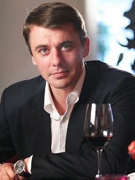 a man sitting at a table with a glass of red wine in front of him