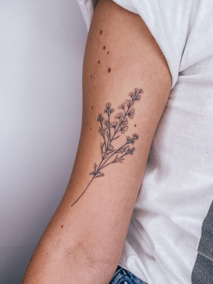 a woman's arm with a tattoo on it that has flowers growing out of it