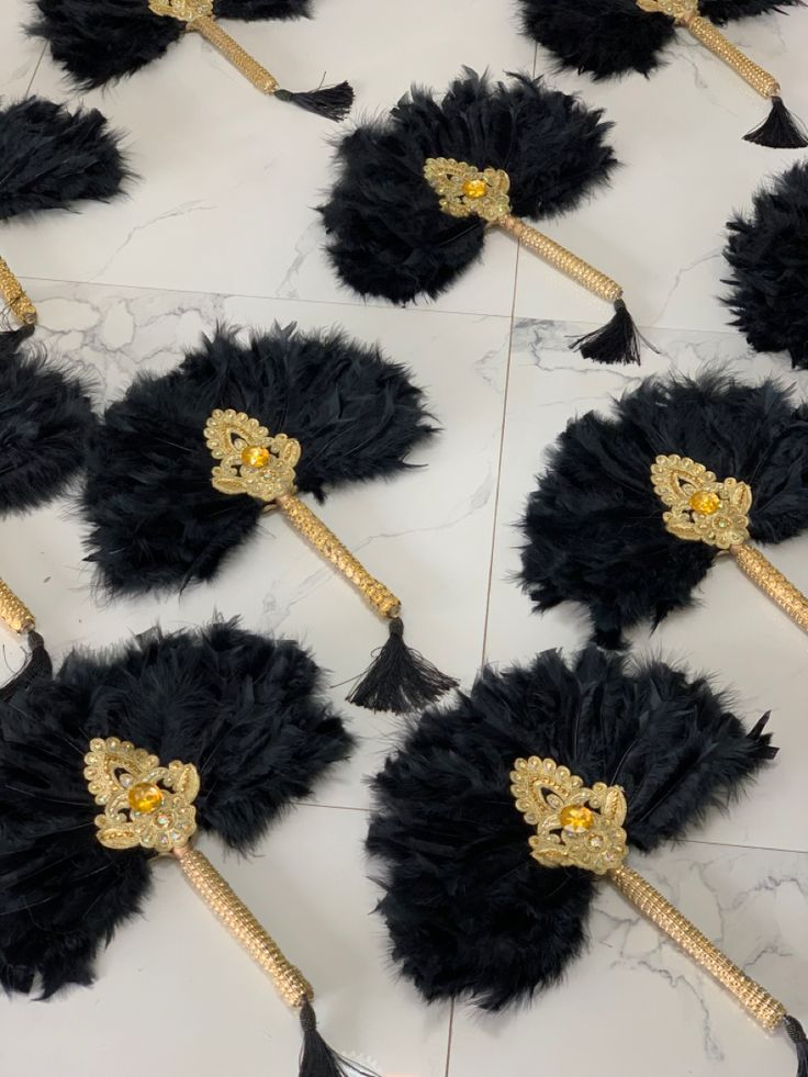 black feathers with gold accents are arranged on a marble surface