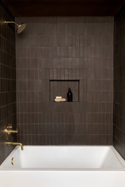 a white bath tub sitting inside of a bathroom next to a wooden ceiling and tiled walls