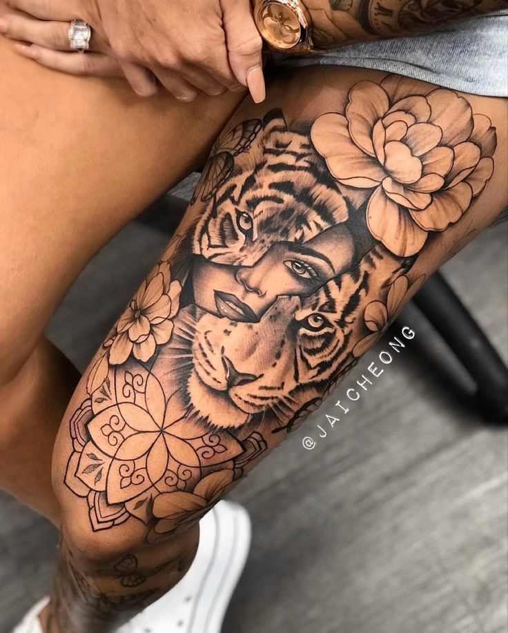 a woman's leg with a tiger and flowers tattoo on it