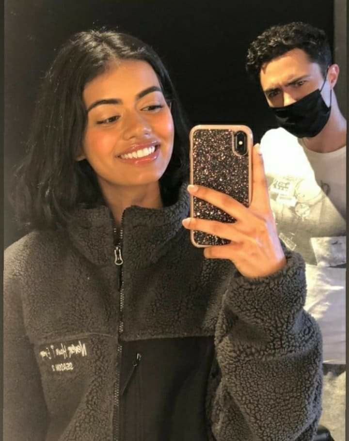 a woman taking a selfie in front of a mirror while wearing a face mask