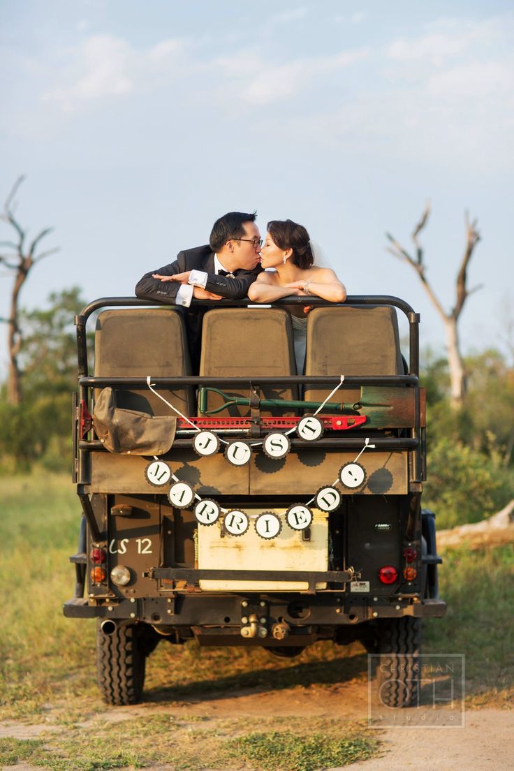 two people are kissing in the back of a safari vehicle with giraffes