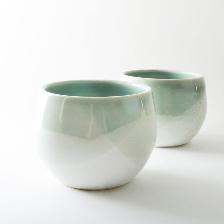 two white and green cups sitting next to each other