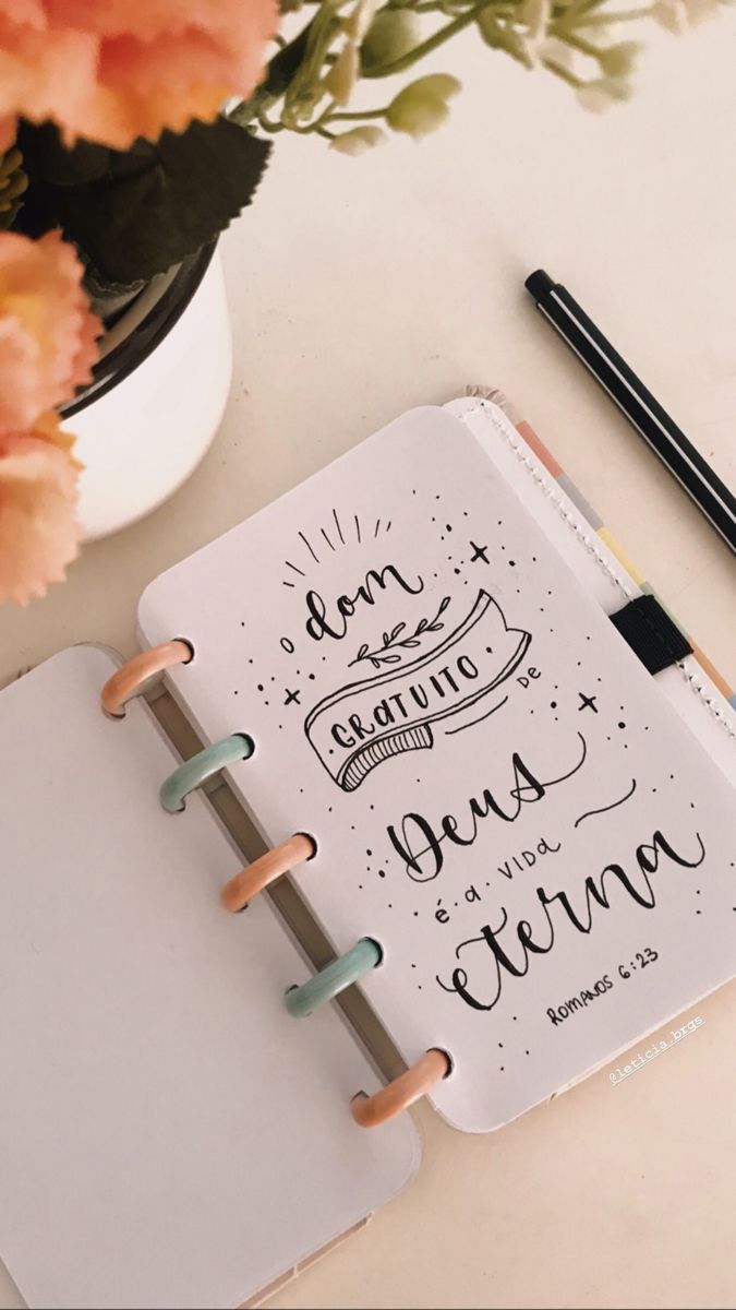 a notebook with some writing on it next to flowers and a cup of pencils