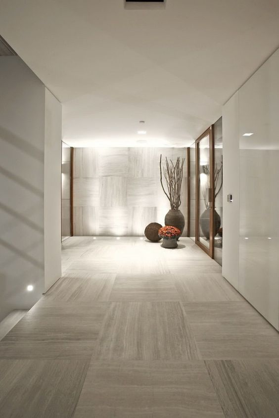 an empty hallway with vases and flowers on the floor