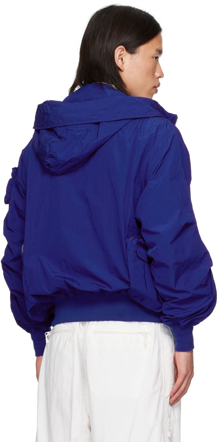 Crinkled nylon taffeta jacket. Water-repellent. · Bungee-style drawstring at hood · Two-way zip closure with button placket · Loops at chest · Zip, cargo, and welt pockets · Rib knit hem and cuffs · Dropped shoulders · Raglan sleeves · Utility pocket at sleeve · Zip and cargo pockets at back · Zip and patch pockets at interior · Full mesh lining Supplier color: R.blue Nylon Hooded Jacket With Functional Drawstring For Streetwear, Nylon Windbreaker With Functional Drawstring For Streetwear, Blue Nylon Outerwear With Double-lined Hood, Blue Nylon Techwear Outerwear, Streetwear Nylon Windbreaker With Functional Drawstring, Blue Nylon Parka With Adjustable Hood, Blue Nylon Hooded Jacket With Double-lined Hood, Blue Nylon Hooded Jacket With Drawstring, Blue Hooded Techwear Windbreaker