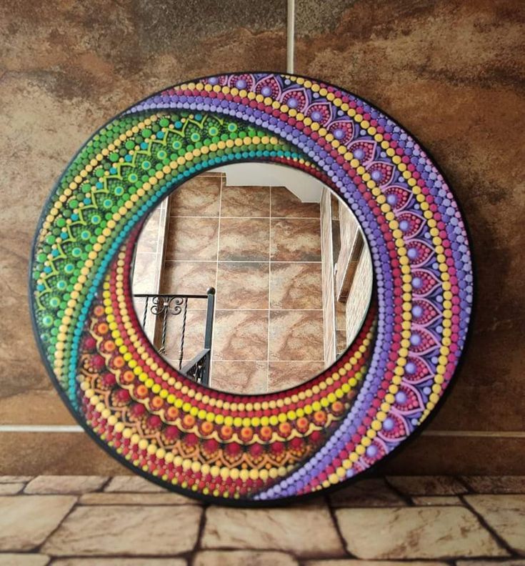 a multicolored circular mirror sitting on top of a tiled floor next to a wall