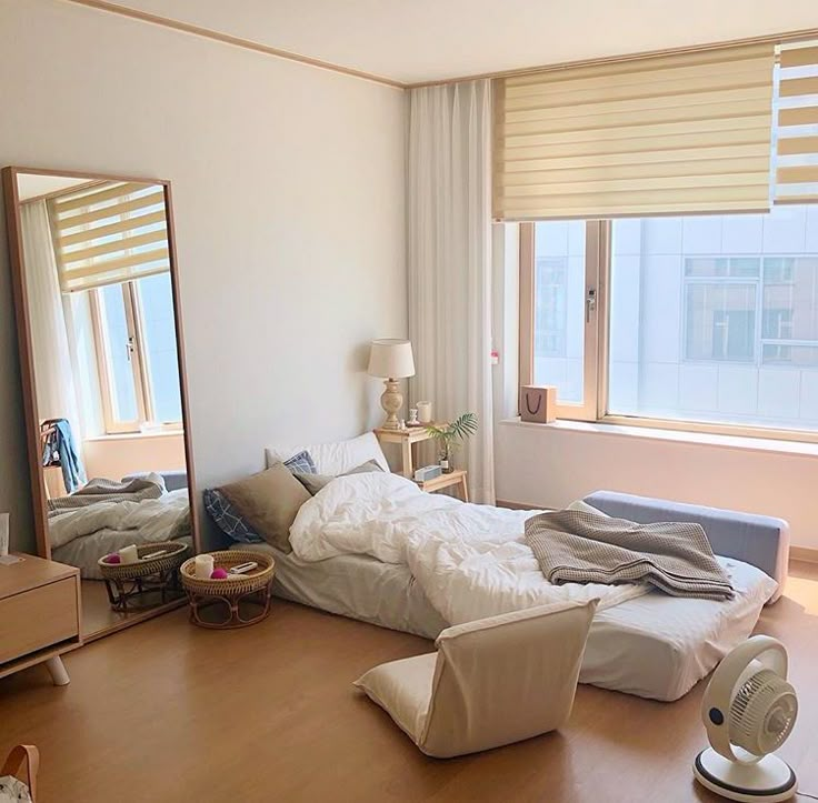 an unmade bed sitting in the middle of a bedroom next to a large window