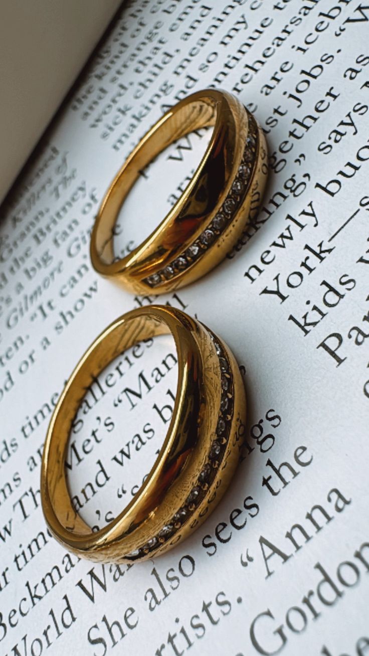 two gold rings sitting on top of an open book