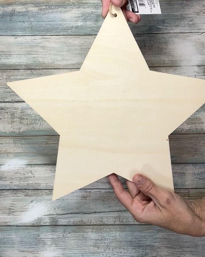 a person holding a wooden star cut out from plywood planks with a tag attached to it