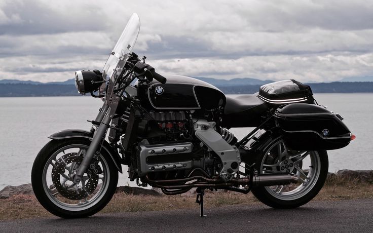 a black motorcycle parked next to the ocean