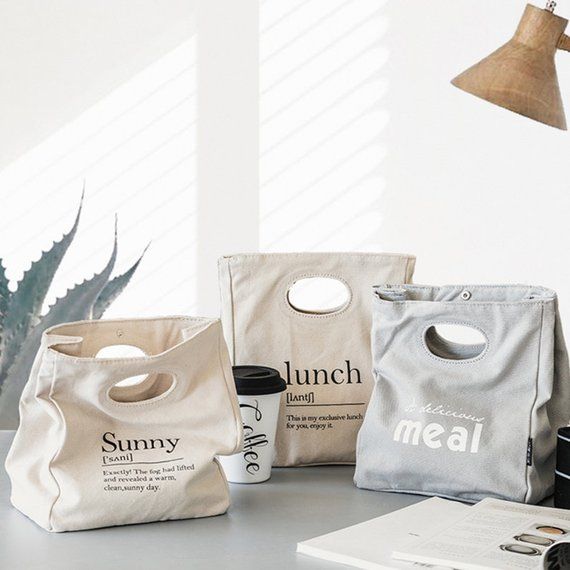 three lunch bags sitting on top of a table next to a coffee cup and book