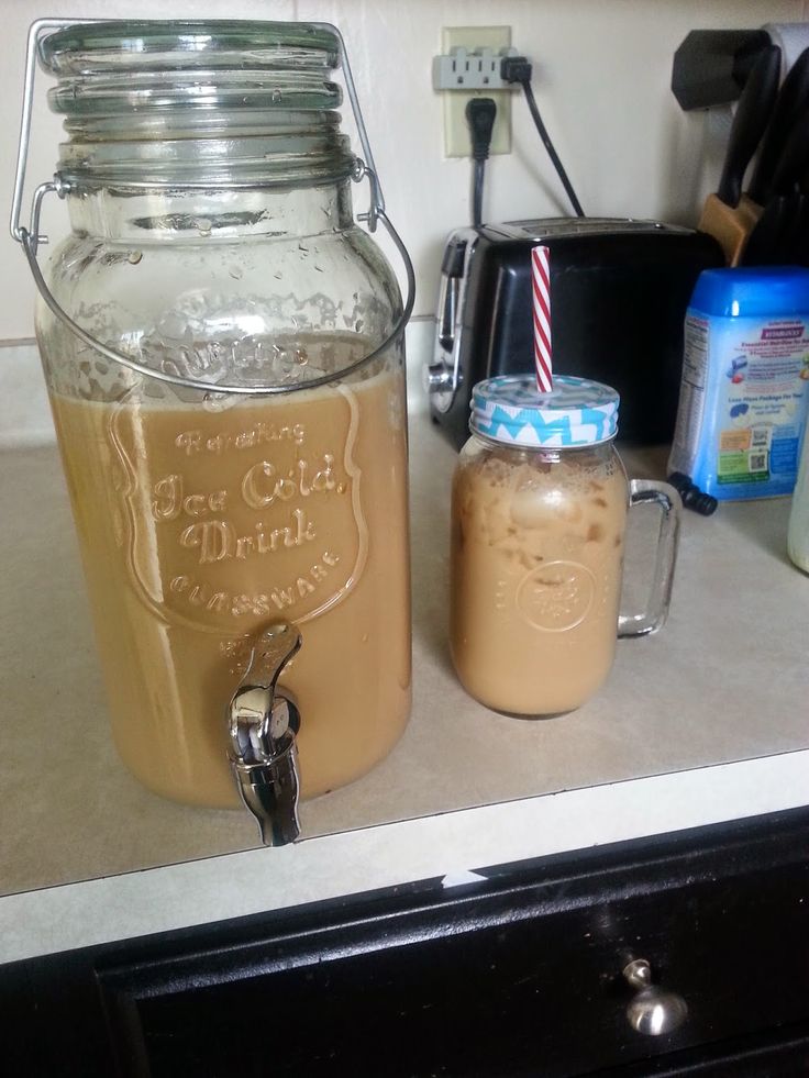 two mason jars filled with liquid sitting on top of a counter next to a blender