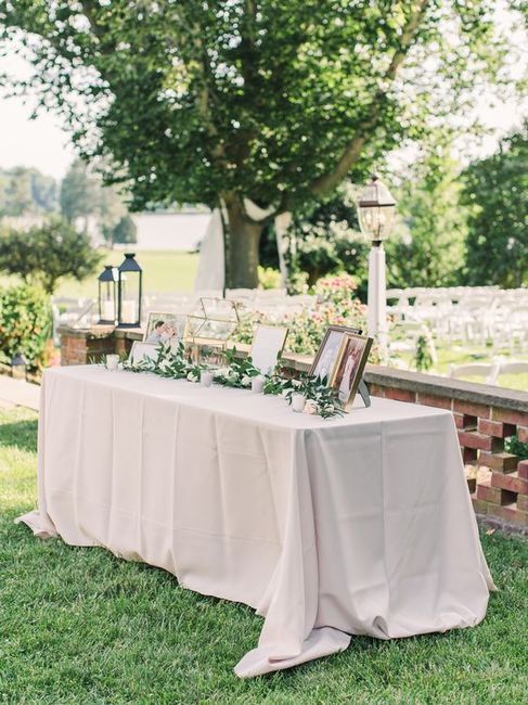 a table with flowers and pictures on it in front of a tree at a wedding