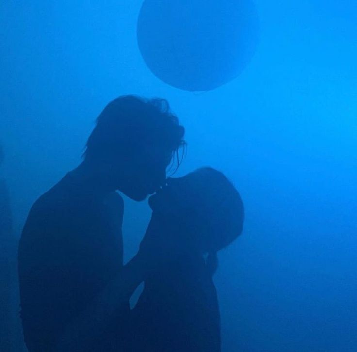 two people are kissing in the dark with balls above their heads on a foggy night