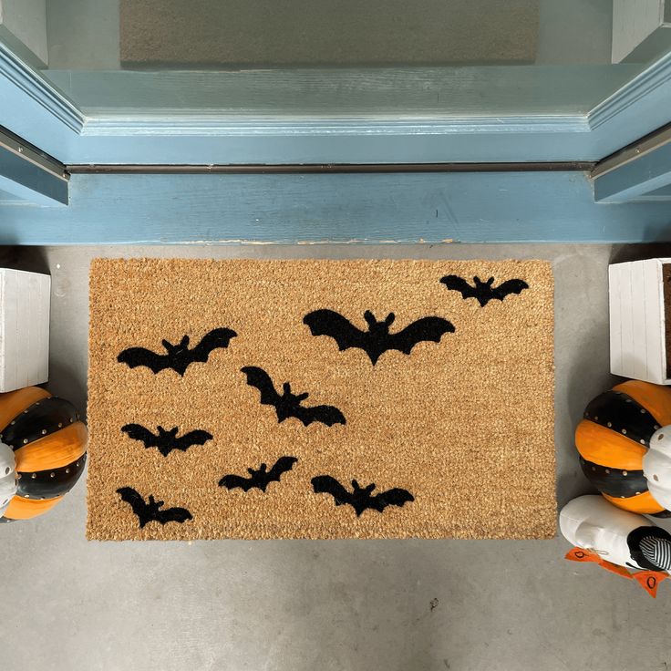 a door mat with bats on it in front of two shoes and an orange pumpkin