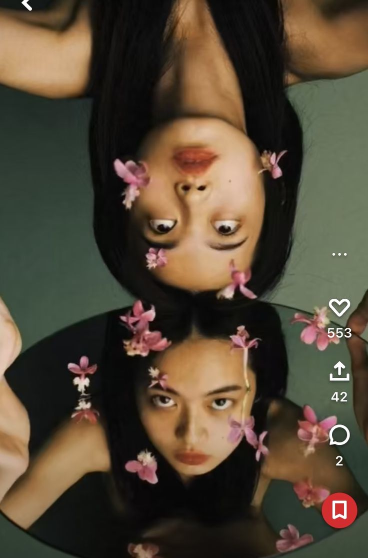 two women with flowers on their heads are reflected in a mirror that is upside down