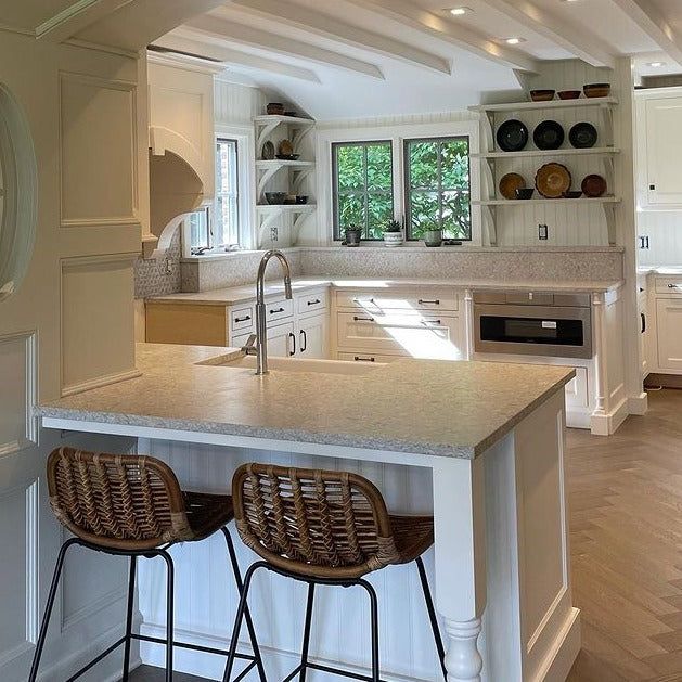 a kitchen with two stools next to an island