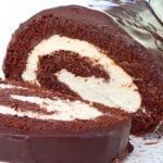 there is a chocolate roll with white frosting on the top and one slice cut out