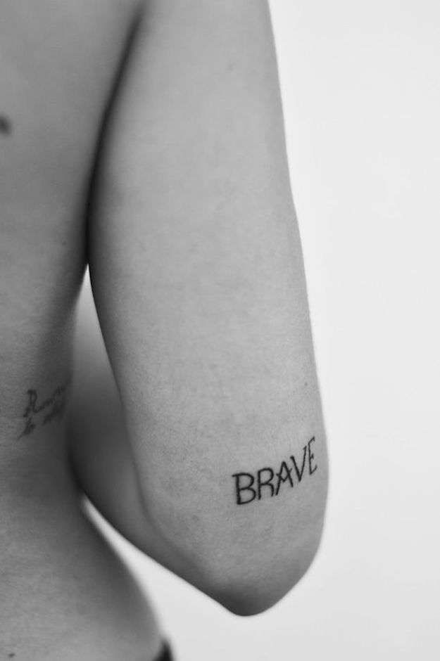 black and white photo of someone's back with the word brave tattooed on it