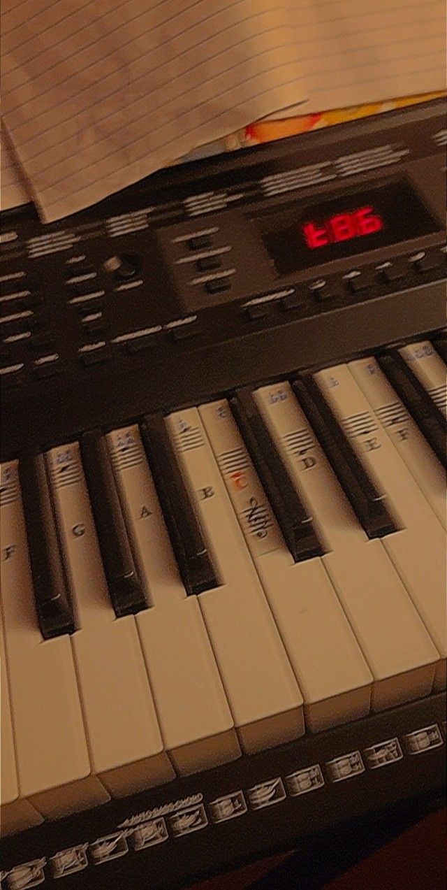 an electronic keyboard with red numbers on the keys and music notes in front of it