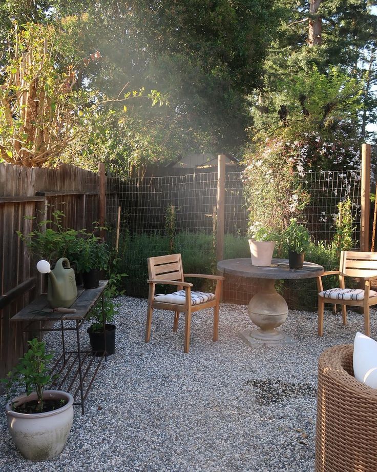 an outdoor patio with chairs, table and potted plants in the back yard area