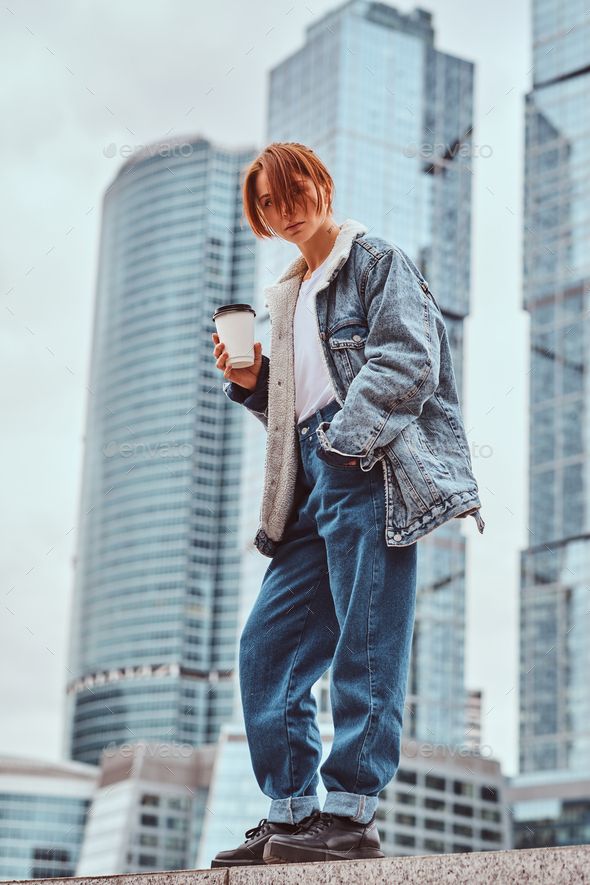 a man standing on the edge of a wall holding a coffee cup in his hand