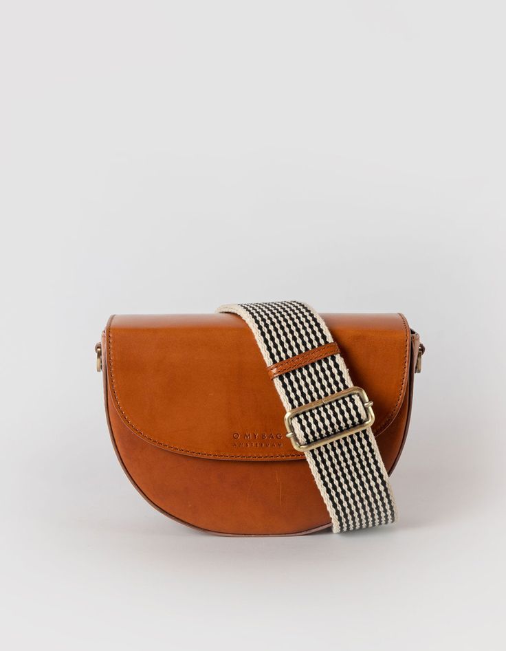 Inspired by our original Meghan bag from 2018, Ava is a modern and refined crossbody bag. The curved silhouette and firm structure make it the perfect saddle bag for street-style lovers with a luxurious touch. The half-moon shape is reminiscent of 90’s New York street style and is just as practical as is beautiful. Finished with an inside zipper pocket and the magnetic closure flap, Ava makes a versatile choice for everyday wear. OMB-E163BV DETAILS One main compartment|One interior slip-in pocket|One interior zip pocket|O My Bag's signature striped cotton lining|Leather strap: 109cm - 124cm|Webbing strap: 85cm - 130cm|Fits the webbing strap|Antique brass hardware SIZE L 23 W 8 H 16.5 cm New York Streetstyle, Classic Leather Bag, Crossbody Saddle Bag, New York Street Style, Sustainable Leather, Antique Brass Hardware, Webbing Strap, My Bag, New York Street