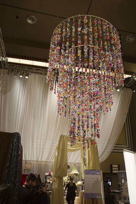 a chandelier hanging from the ceiling in front of a white drape covered stage