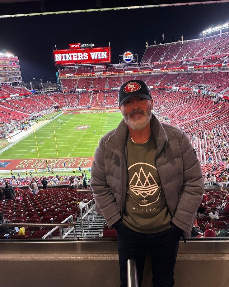 a man sitting in the stands at a football stadium with his hands on his hips