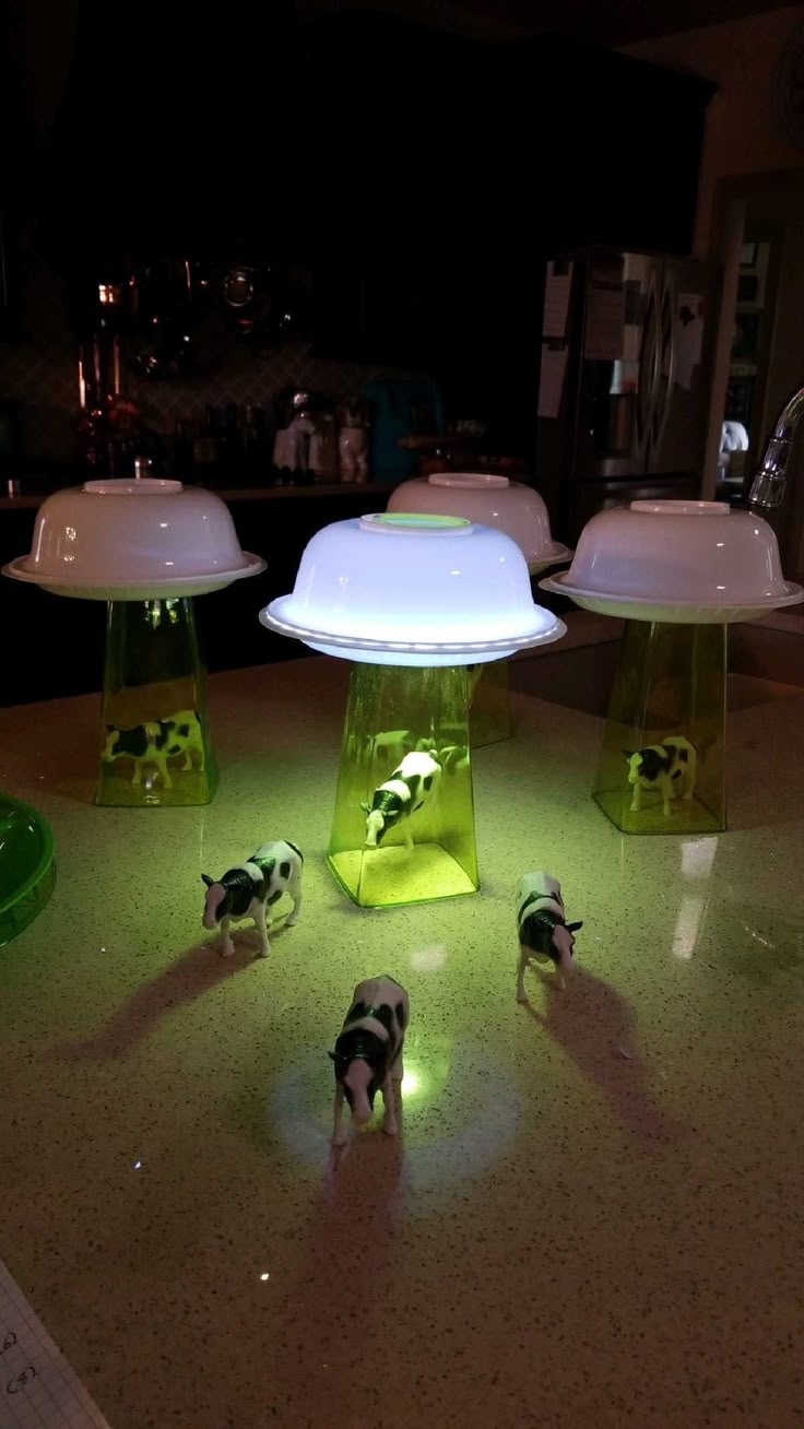 three small toy animals standing on top of a counter next to two large white lights