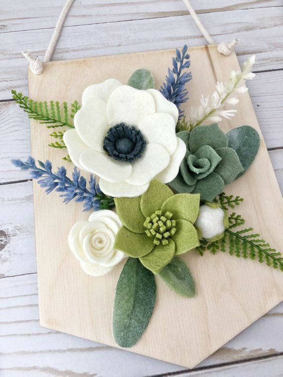 a wooden board with flowers on it and green leaves around the edges, hanging from a rope