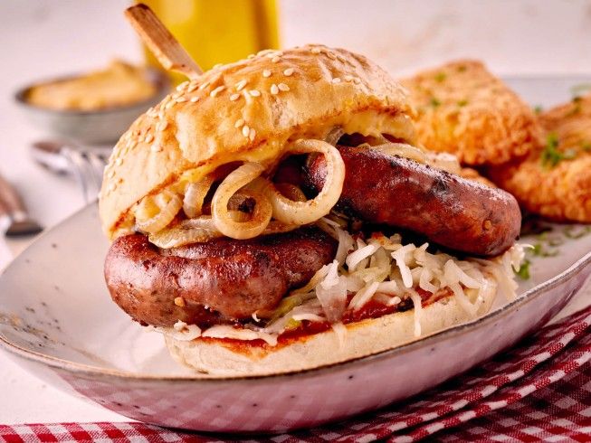 a sausage sandwich with onions and cheese on a plate