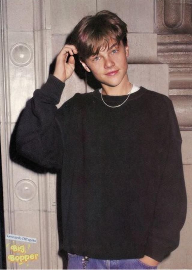 a young man is standing in front of a door and talking on his cell phone