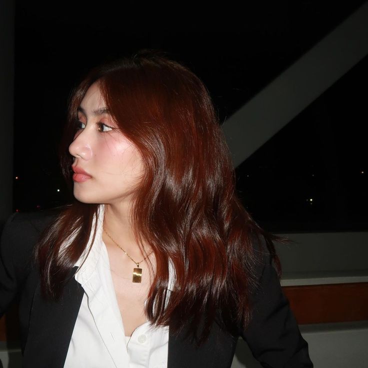 a woman wearing a black blazer and white shirt is looking off into the distance