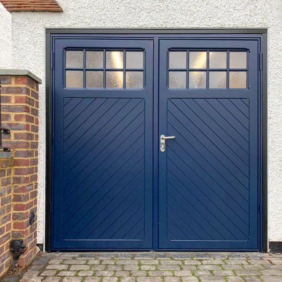 two blue double doors in front of a brick wall and white building with red bricks on the side