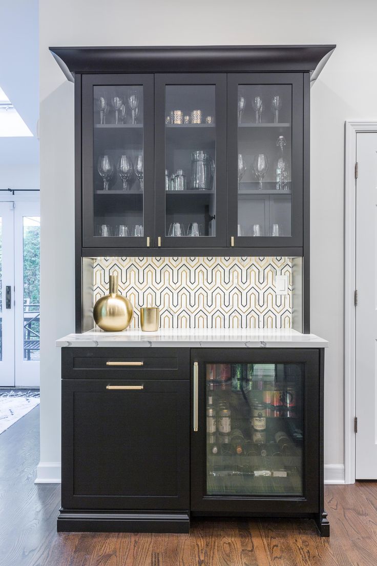 a kitchen with black cabinets and white counter tops, gold accents on the backsplash