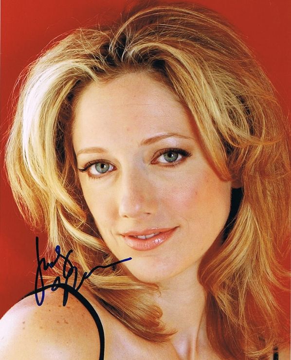 a woman with blonde hair and blue eyes is posing for a photo in front of a red background