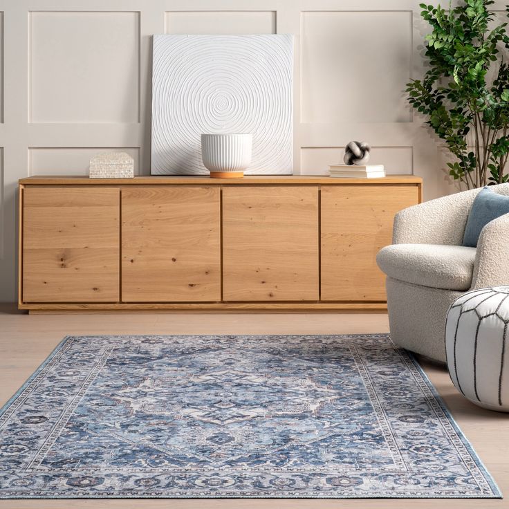 a living room with a rug, chair and sideboard on the floor in front of it